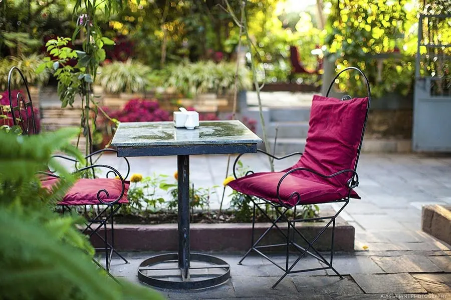 Garden table with red chairs among flowers