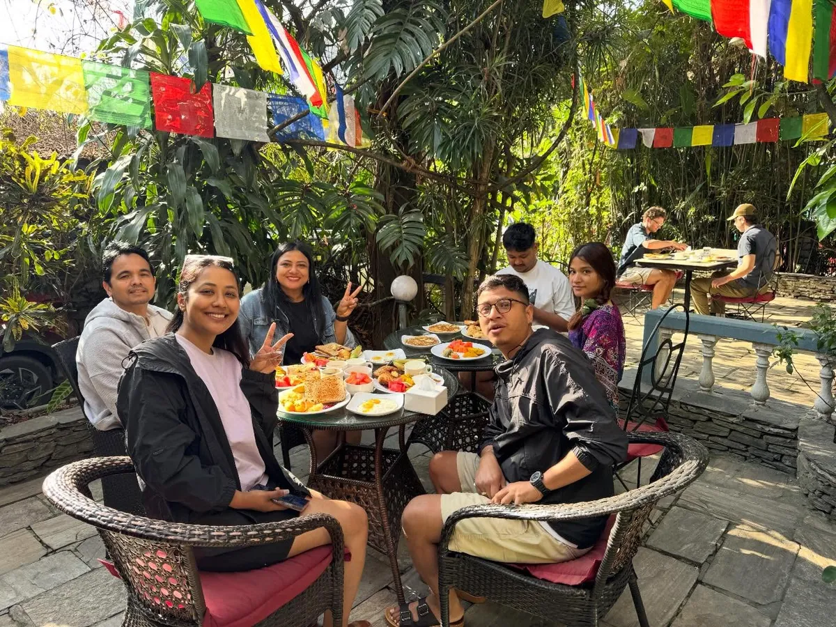 Guests enjoying breakfast together in the garden under prayer flags